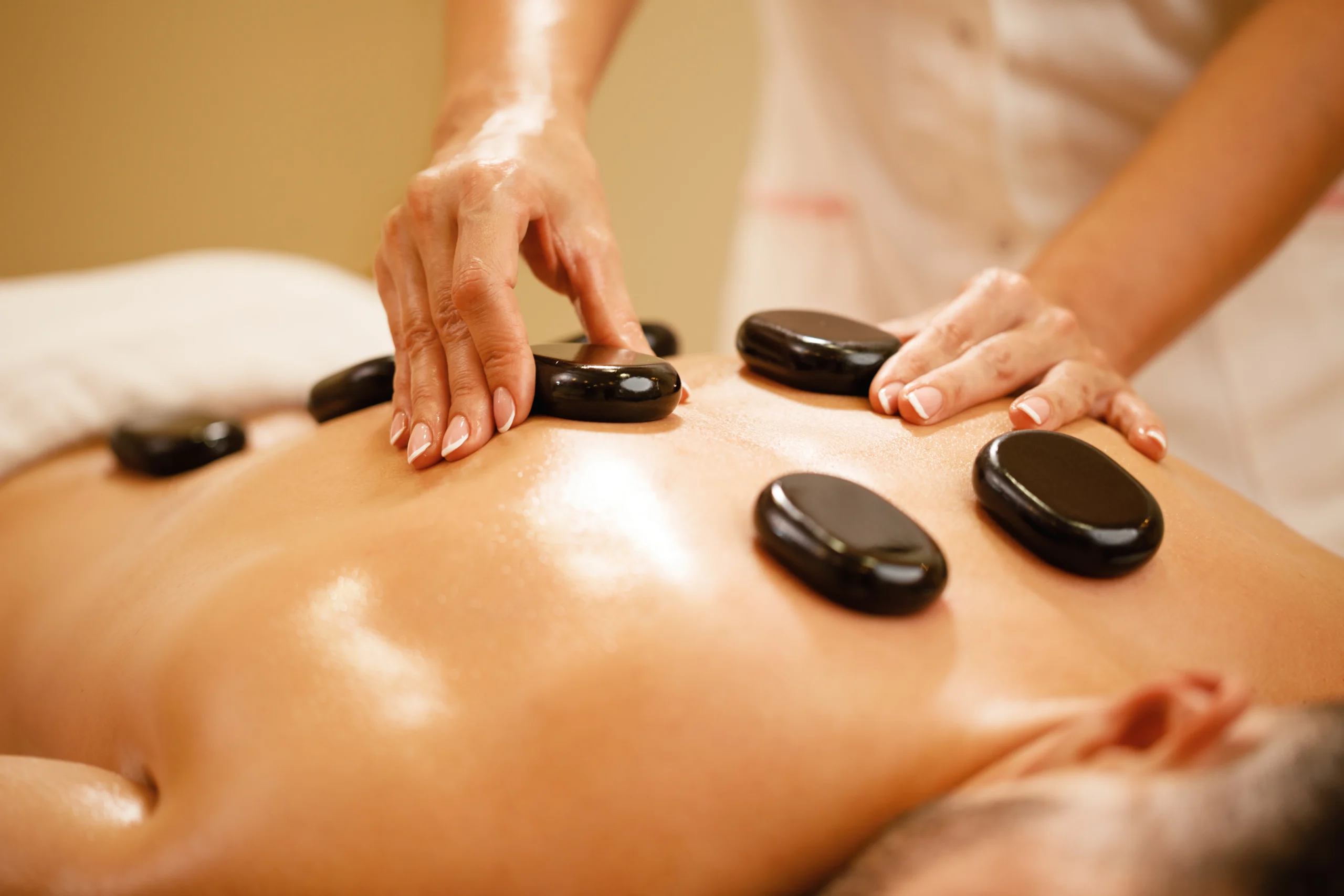 closeup-therapists-placing-hot-stones-man-s-back-lastone-therapy-spa